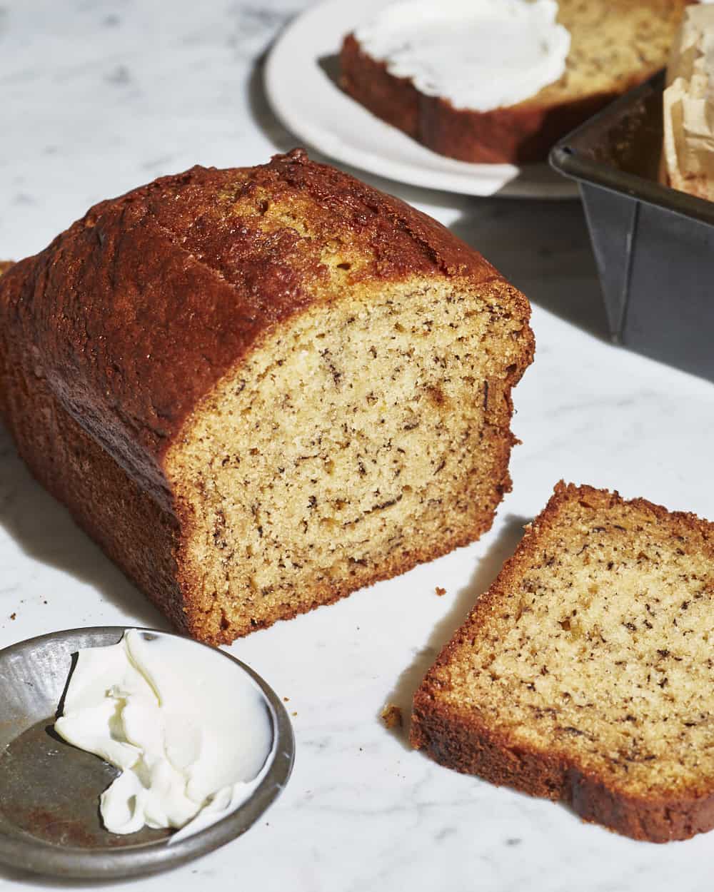 a loaf of banana bread sliced on a marble table