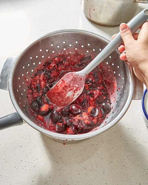 pushing damson puree through colander