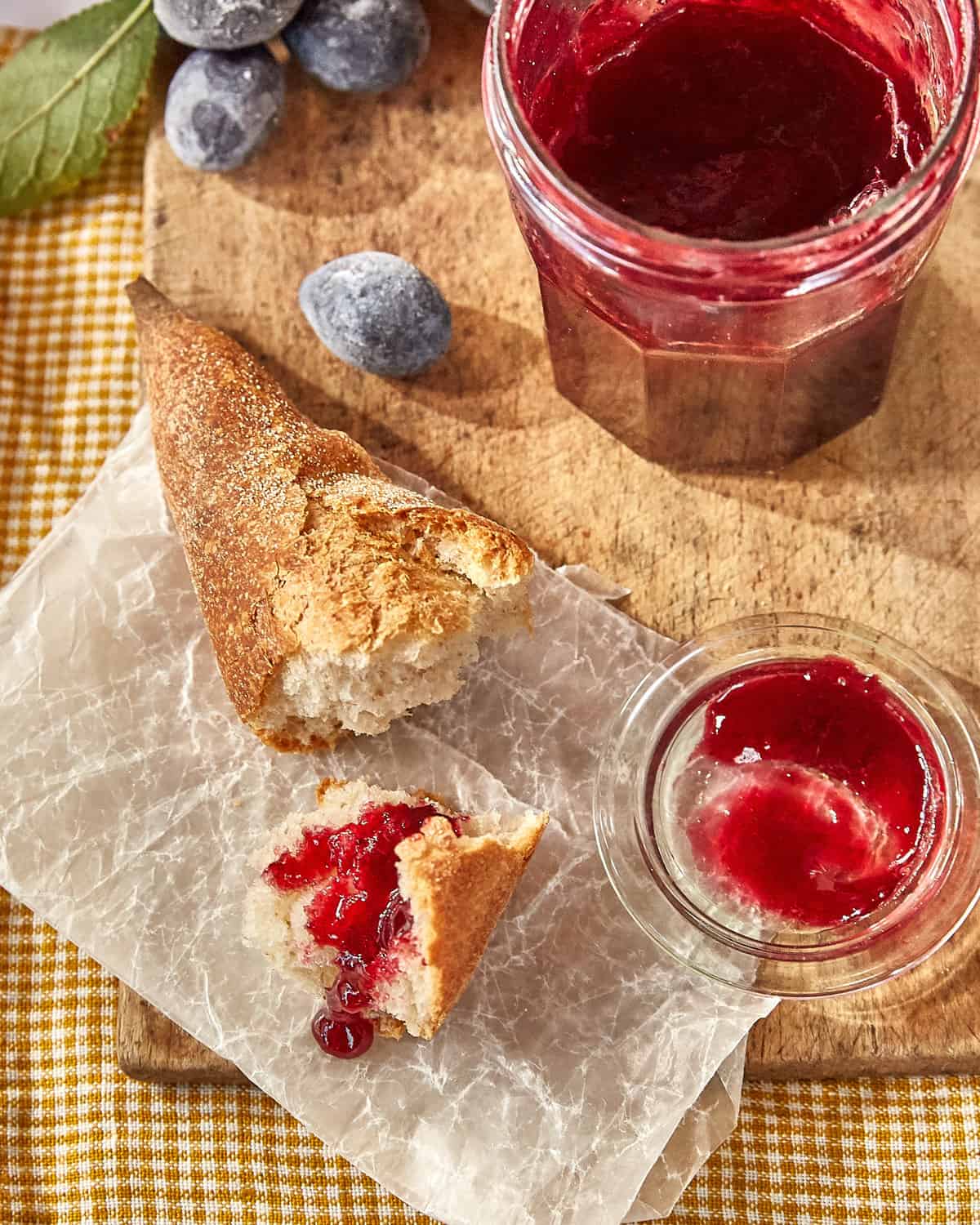 a jar of damson jam next to some baguette with jam