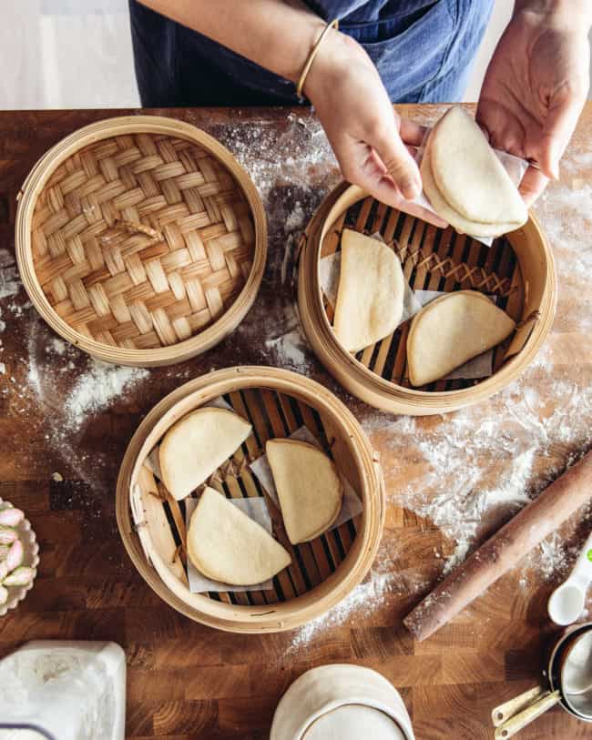 placing shaped bao buns into a bamboo steamer