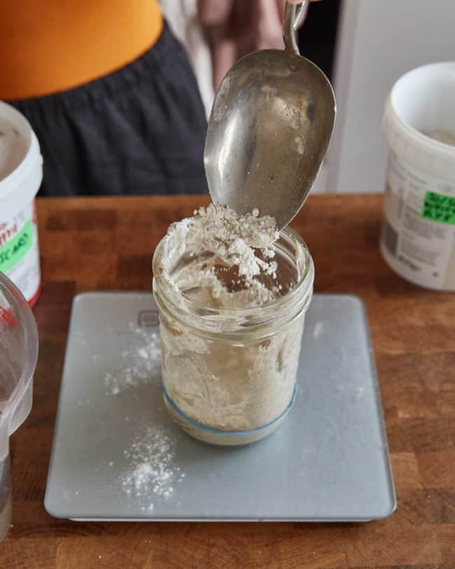 adding flour to the sourdough starter to feed it