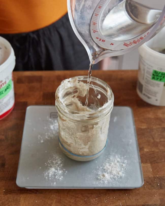 adding water to the sourdough starter to feed it