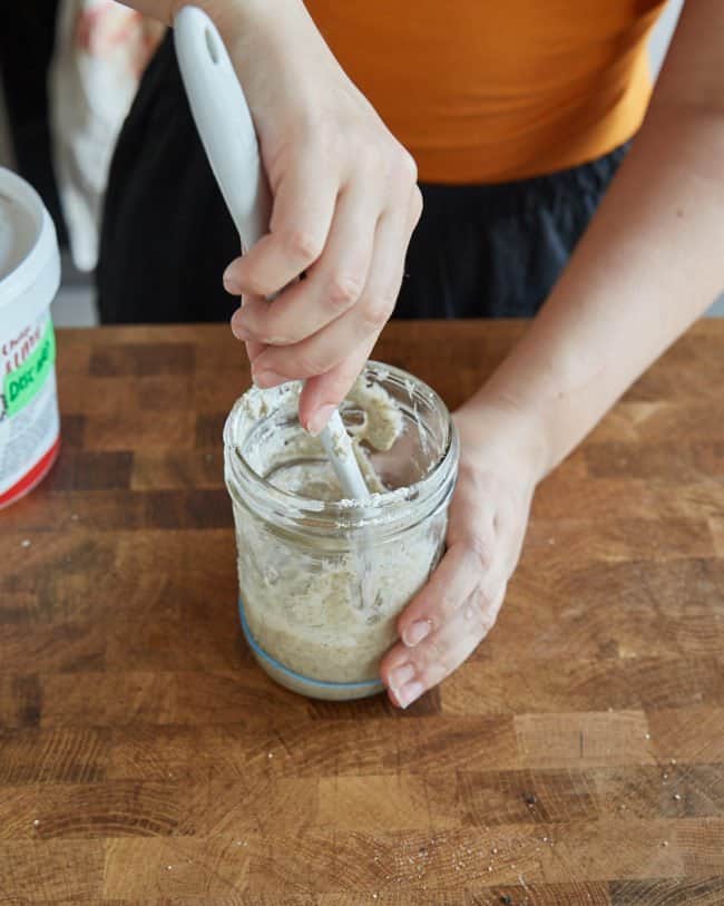 mixing the flour and water into the sourdough starter in a jar