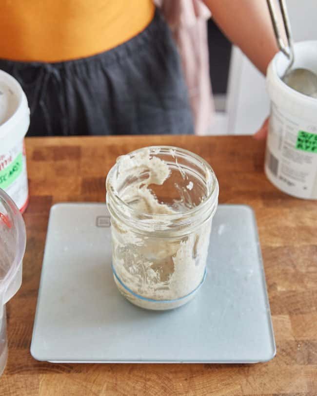 placing a jar of sourdough starter onto weighing scales