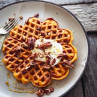 a plate with a pumpkin spice waffle and yoghurt and pecans on top