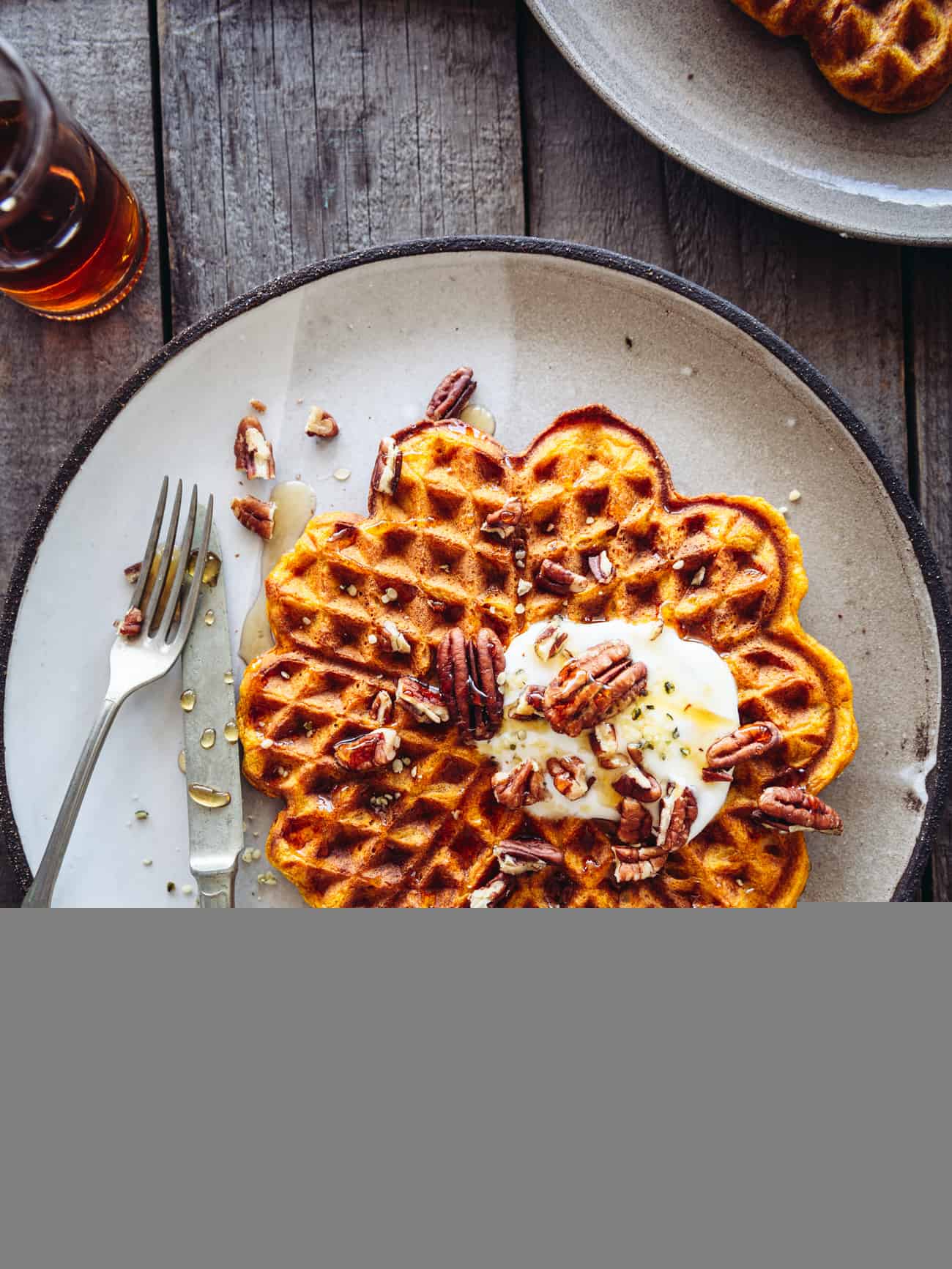 pumpkin spice waffles overhead on a table with maple syrup and pecans