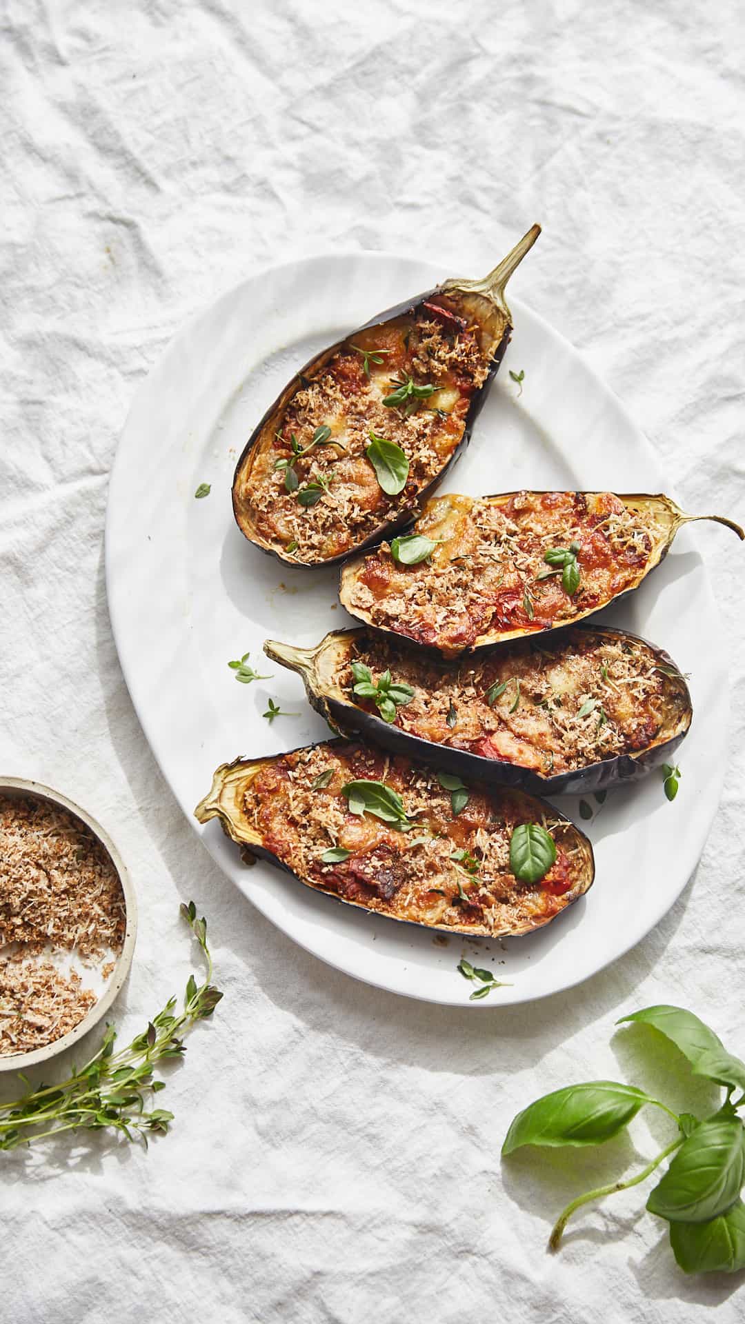 a plate of stuffed aubergine halves with tomato, mozzarella and basil