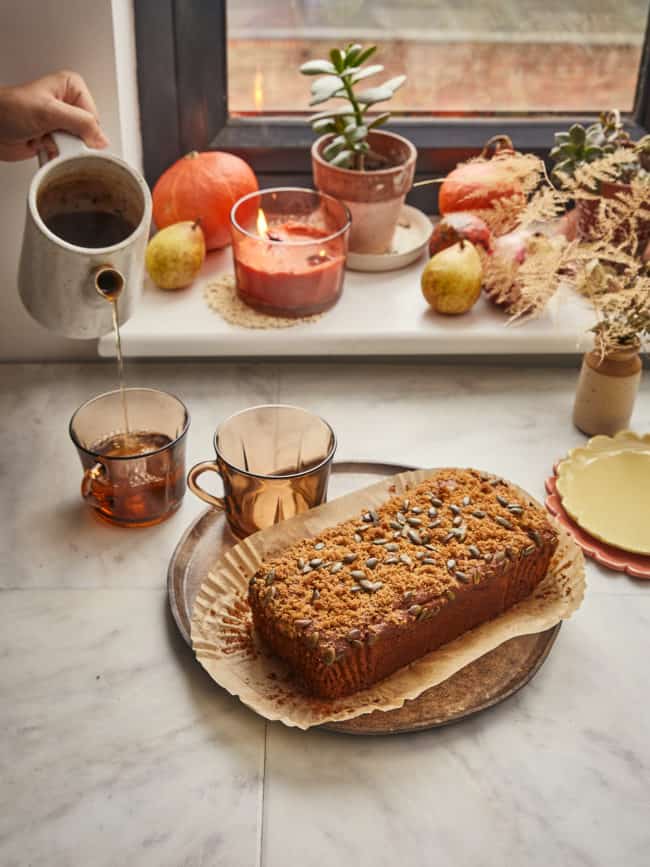 a loaf of vegan sourdough pumpkin bread with tea being poured and winter squash 