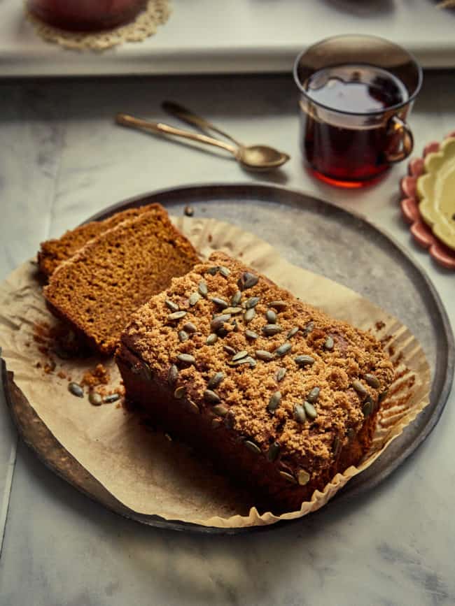 a sliced sourdough pumpkin loaf on a plate with a cup of tea