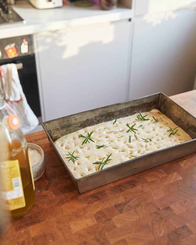 sourdough focaccia dough in a baking tray on a counter