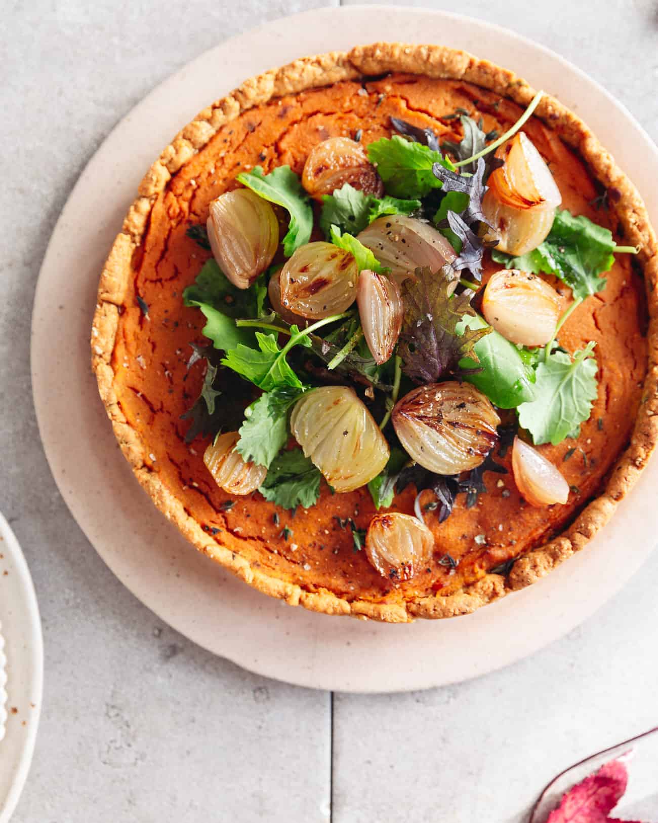 a vegan butternut squash tart topped with baby kale and caramelised shallots