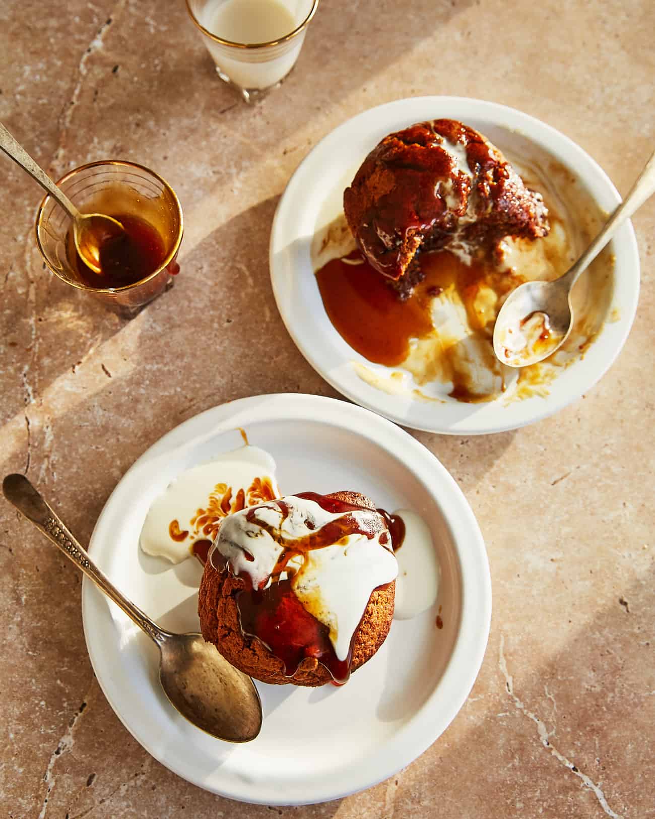 vegan sticky toffee puddings for two, individual servings on plates drizzled with dairy free toffee sauce