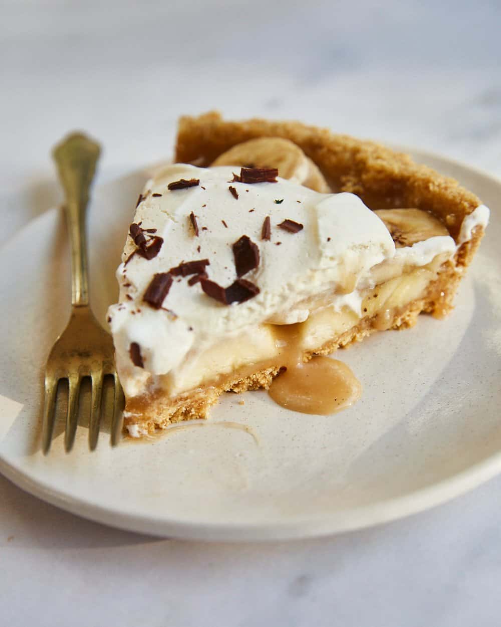 a slice of vegan banoffee pie on a white plate with a fork