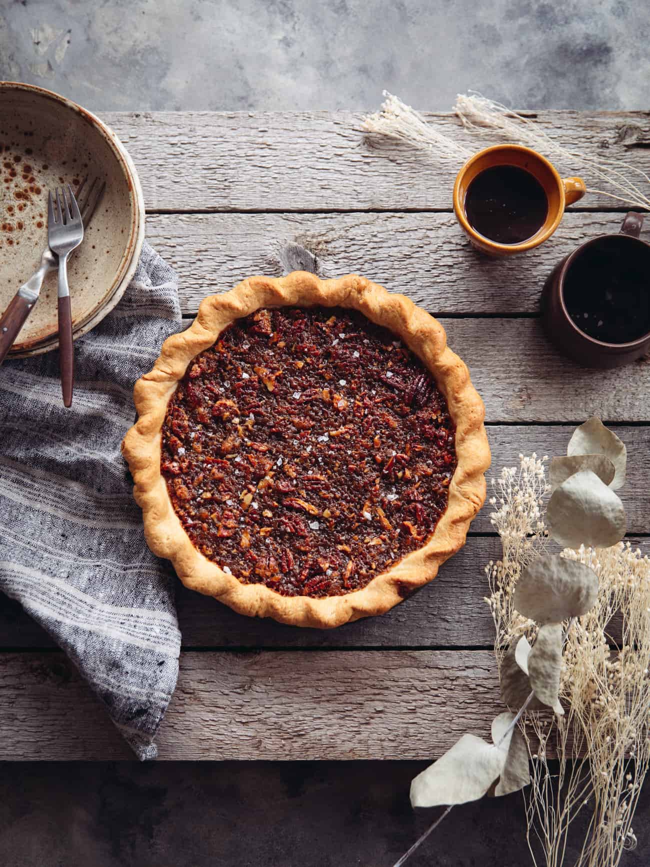 a maple pecan pie overhead with coffee mugs